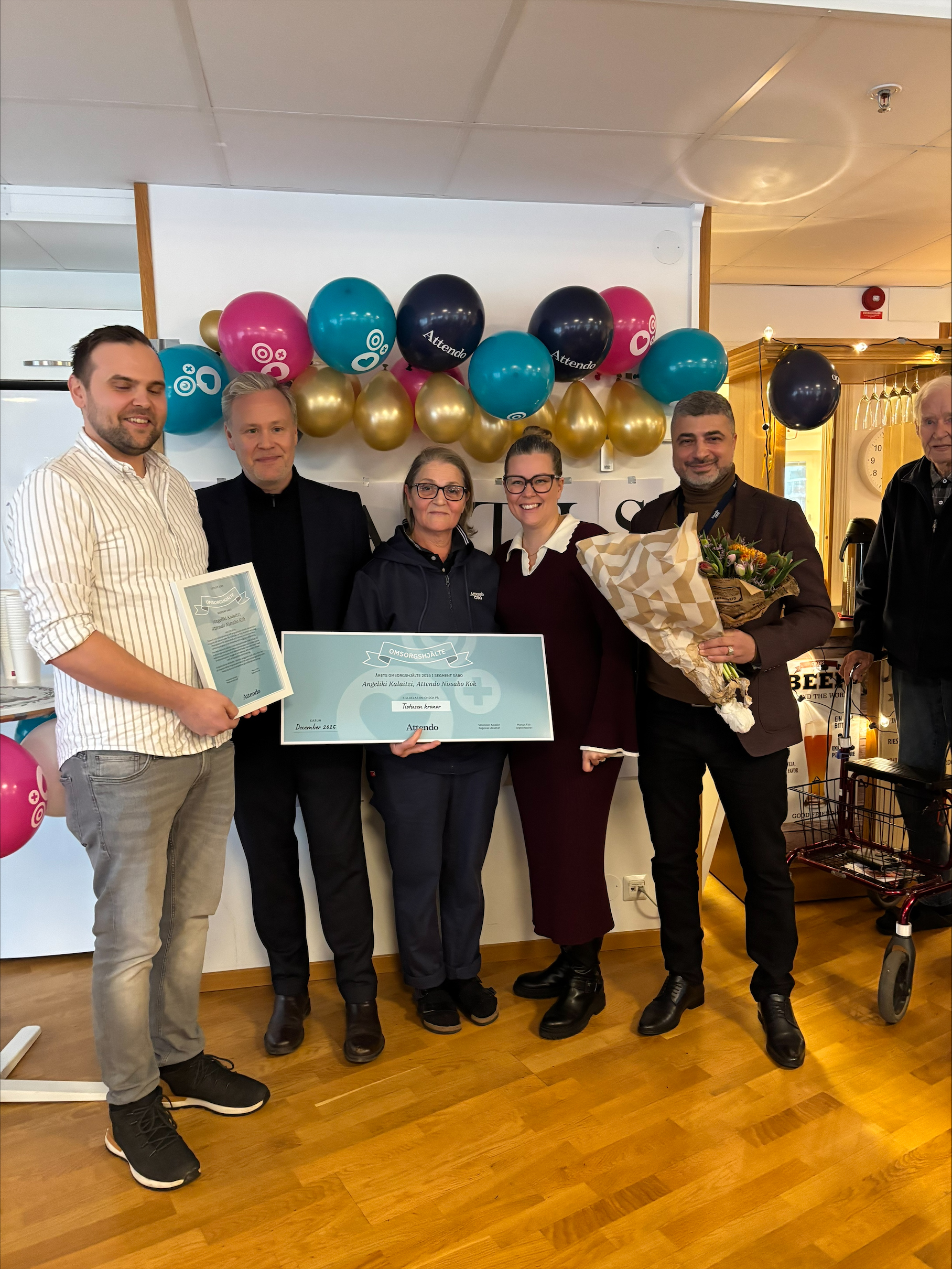 Årets omsorgshjälte segment säbo håller check i handen och omgiven av hyllande chefer