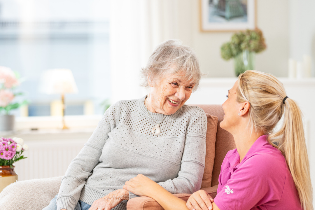 Kvinnlig boende och personal från Attendo ler mot varandra