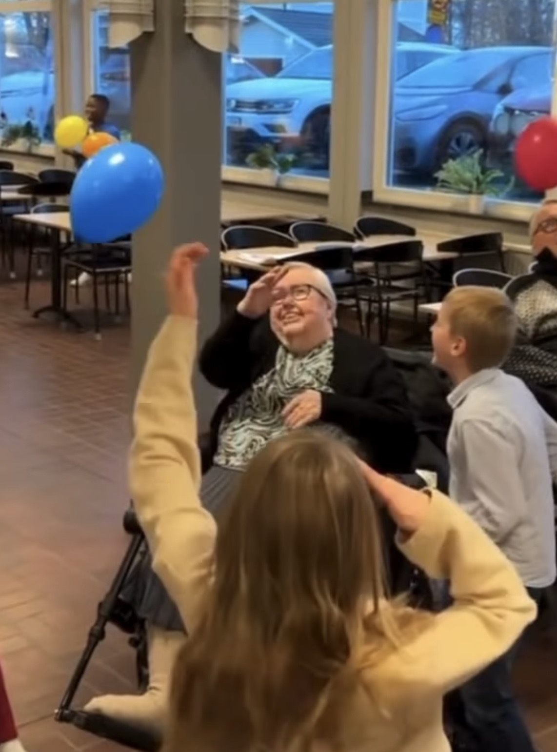 &Auml;ldre dam i rullstol leker med ballonger med eleverna och skrattar.