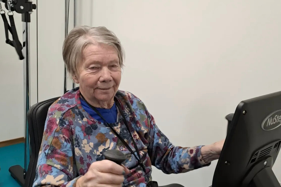 Leende kvinna fr&aring;n &auml;ldreboendet Hamnparken tr&auml;nar p&aring; maskin i gymmet