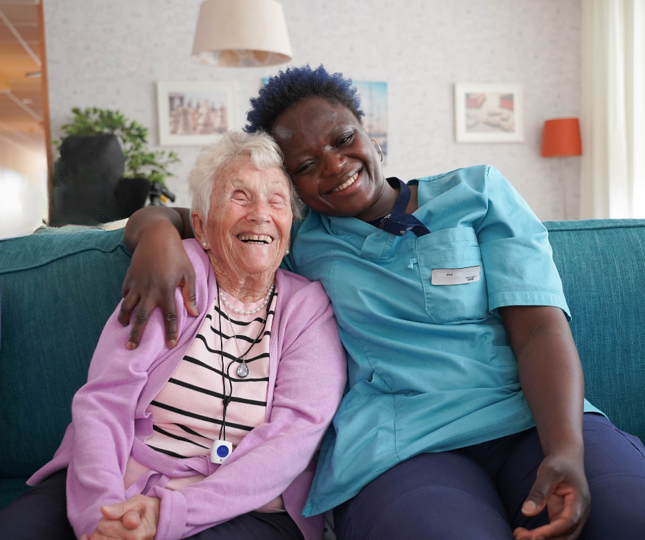 En kvinnlig boende tillsammans med en kvinnlig medarbetare, sitter tillsammans i soffan och skrattar