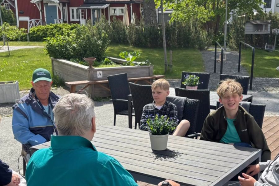 Tv&aring; &auml;ldre m&auml;n och tv&aring; pojkar sitter tillsammans och samtalar.