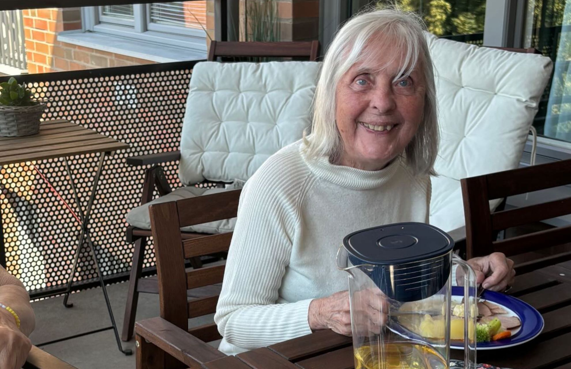Kvinna på äldreboende sitter på uteplats, på väg att hugga in i en god måltid.