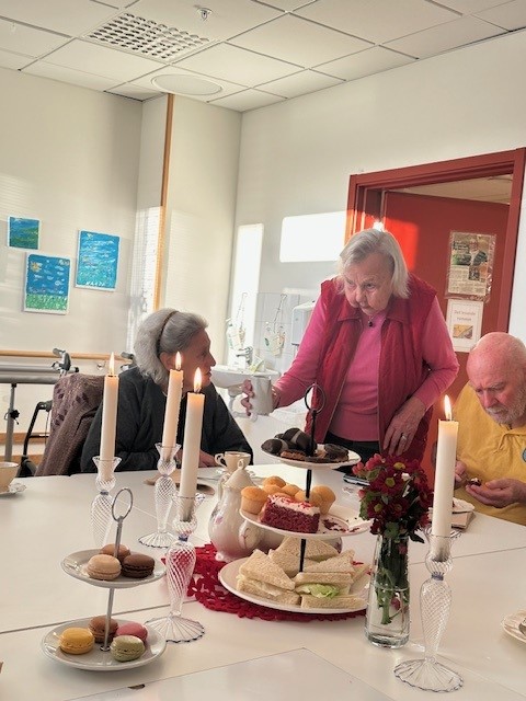 En boende hjälper en annan med mjölk i teet