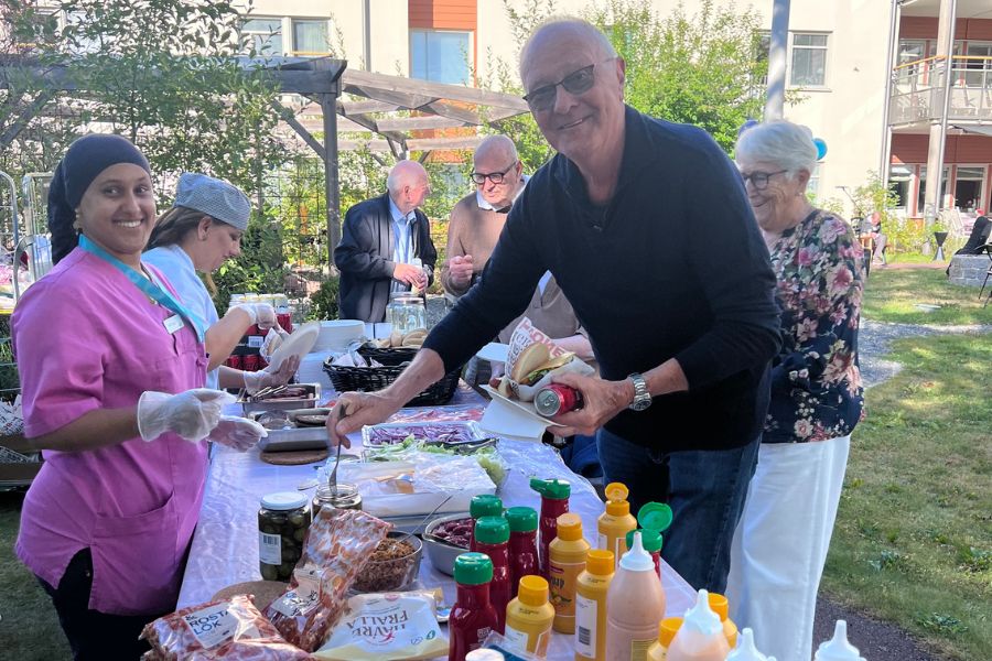 Personal från Attendo servar gästerna med mat från en grillbuffe